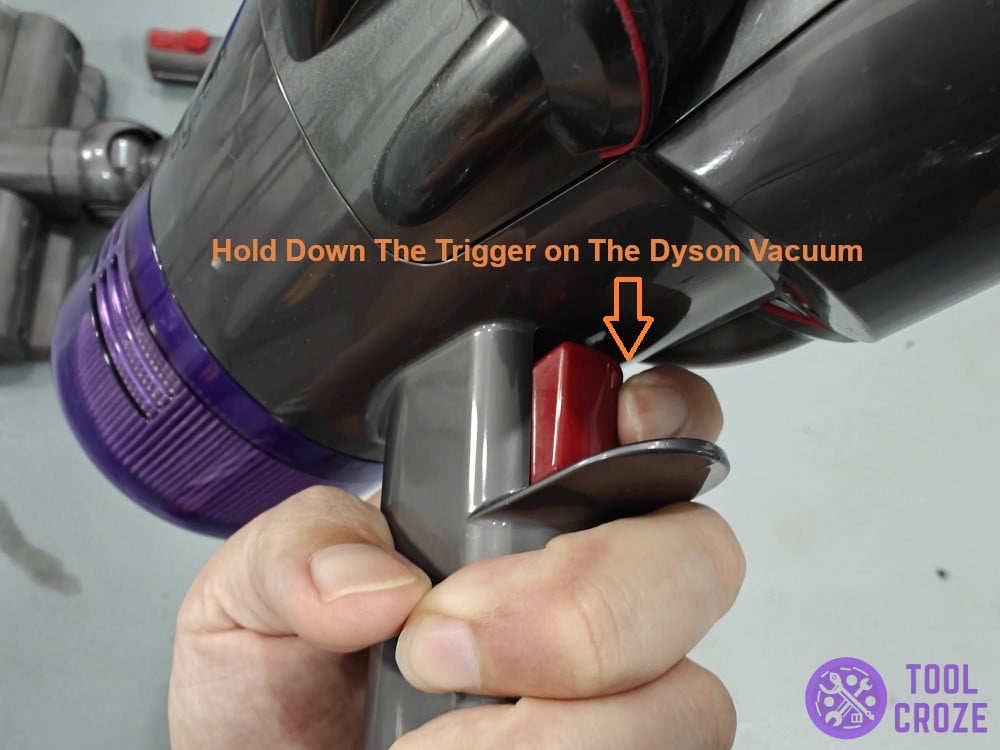 hold down the trigger on the Dyson vacuum