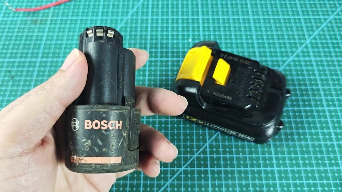 Bosch battery held near DeWalt battery on grid mat