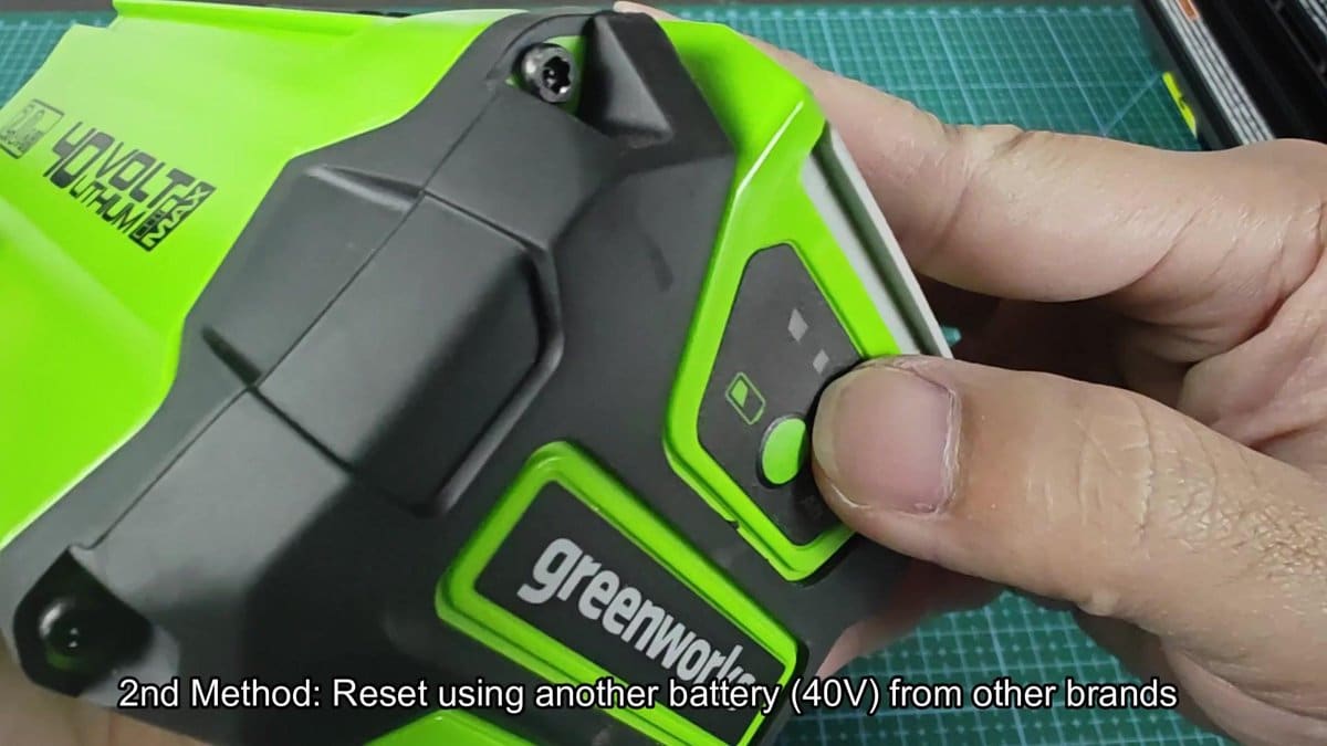 Greenworks 40V battery reset button being pressed