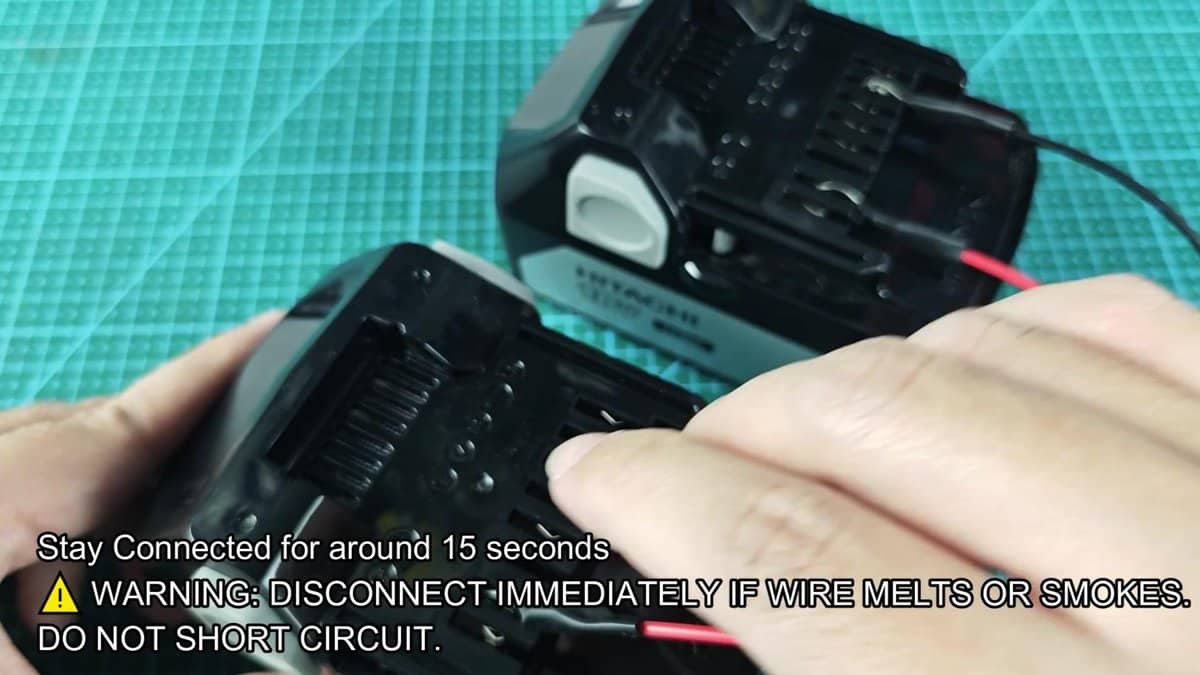 Makita battery packs on green mat with warning text