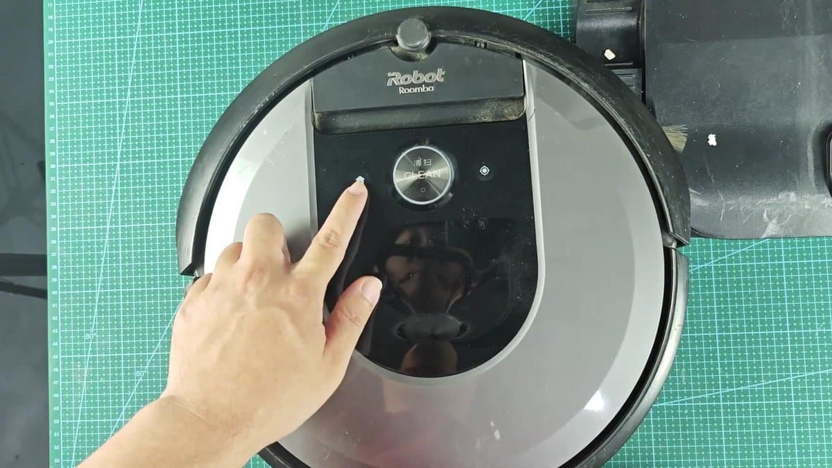 Roomba vacuum with button being pressed