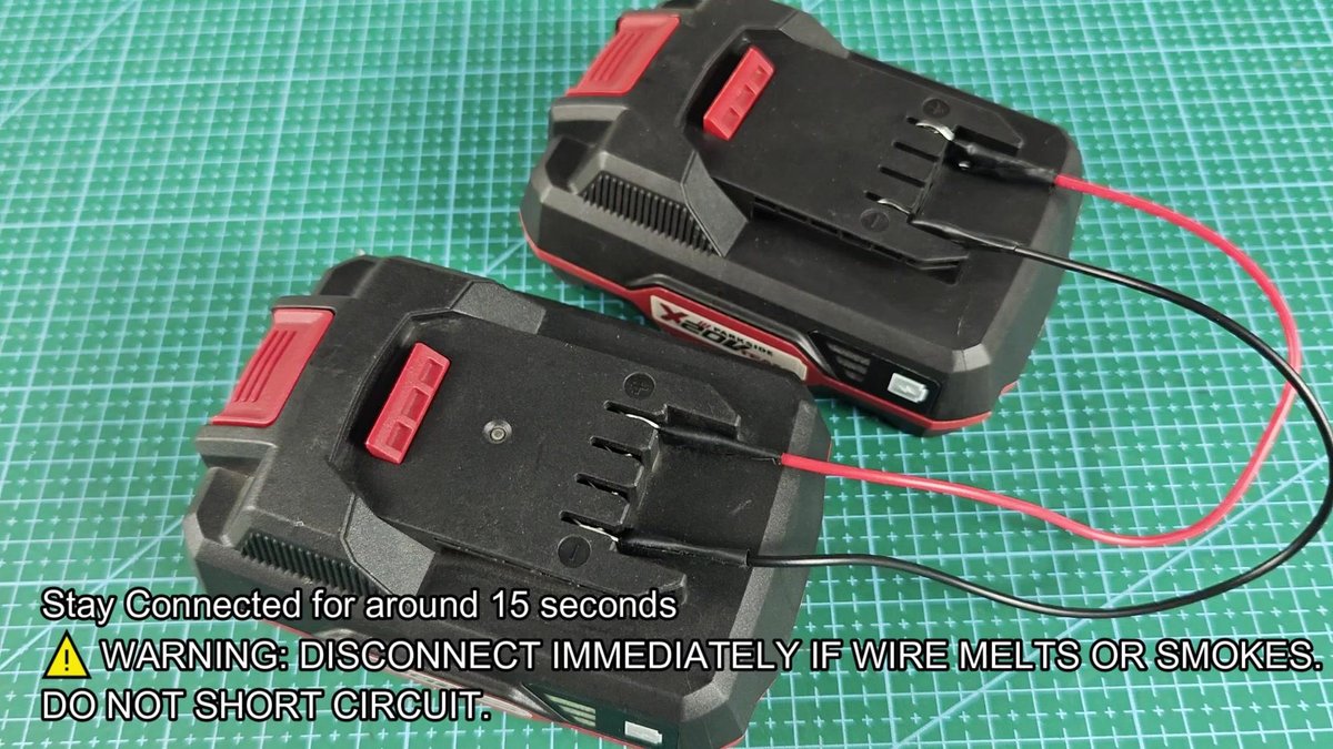 Two batteries connected with wires on grid mat