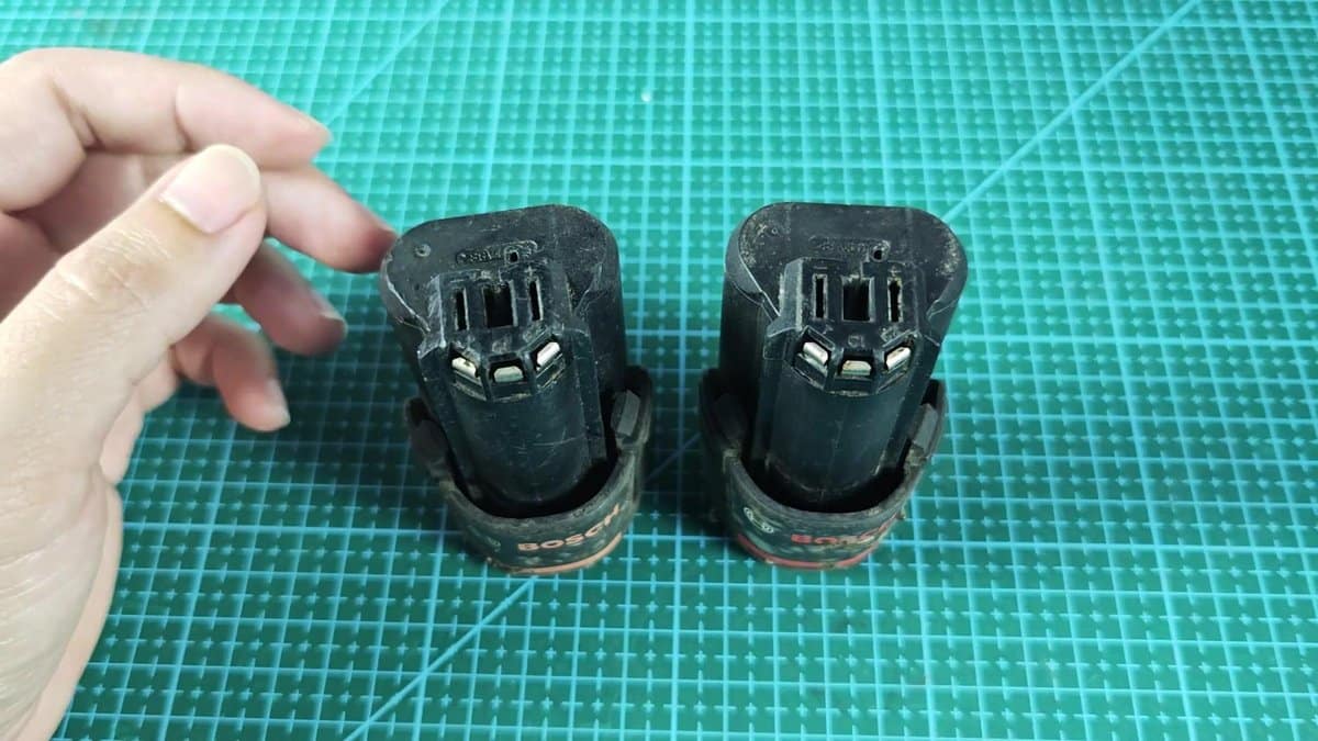 Two Bosch 12V battery packs on green mat