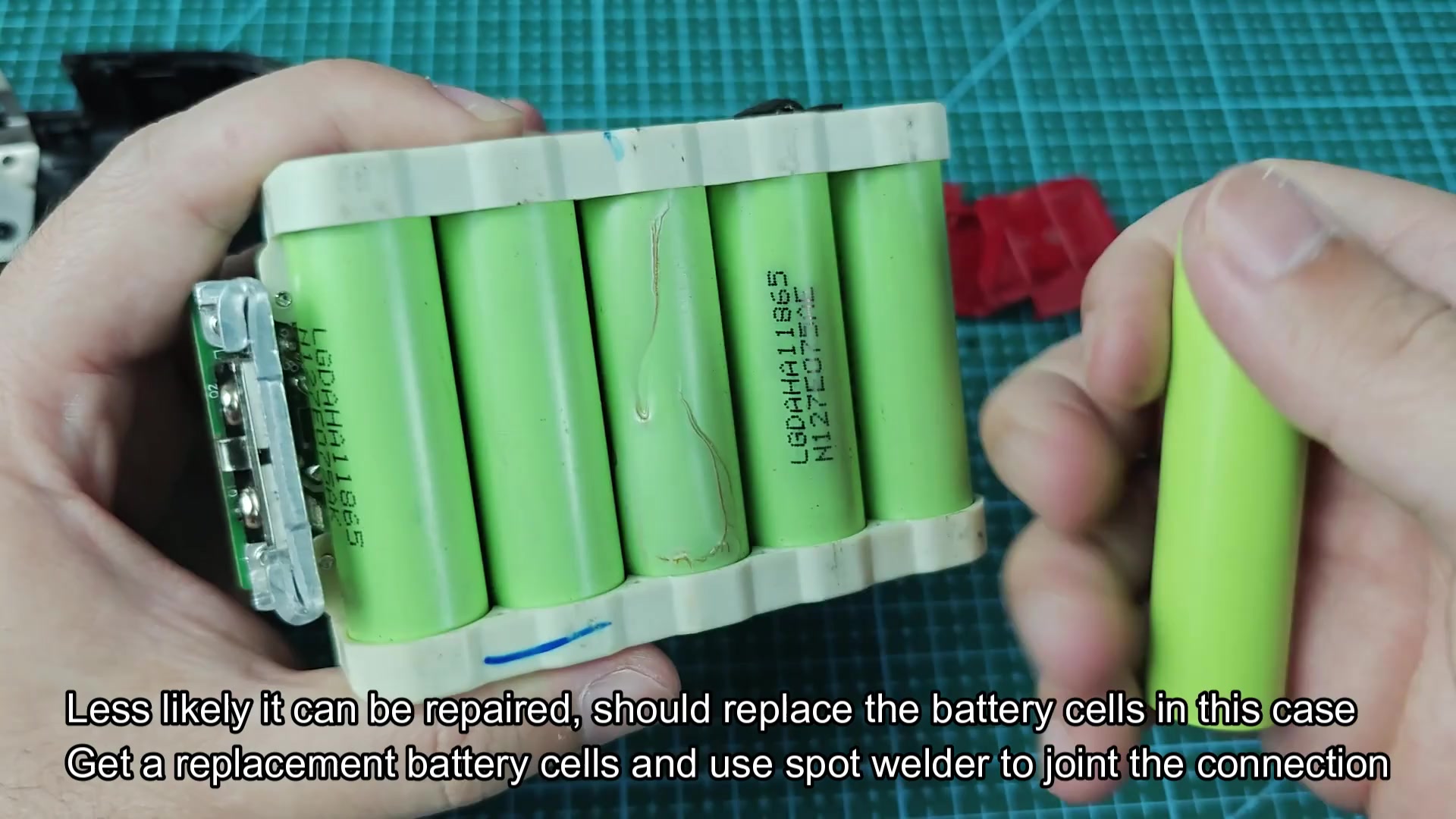 Battery pack top terminals with single replacement cell held nearby Battery pack top terminals with single replacement cell held nearby
