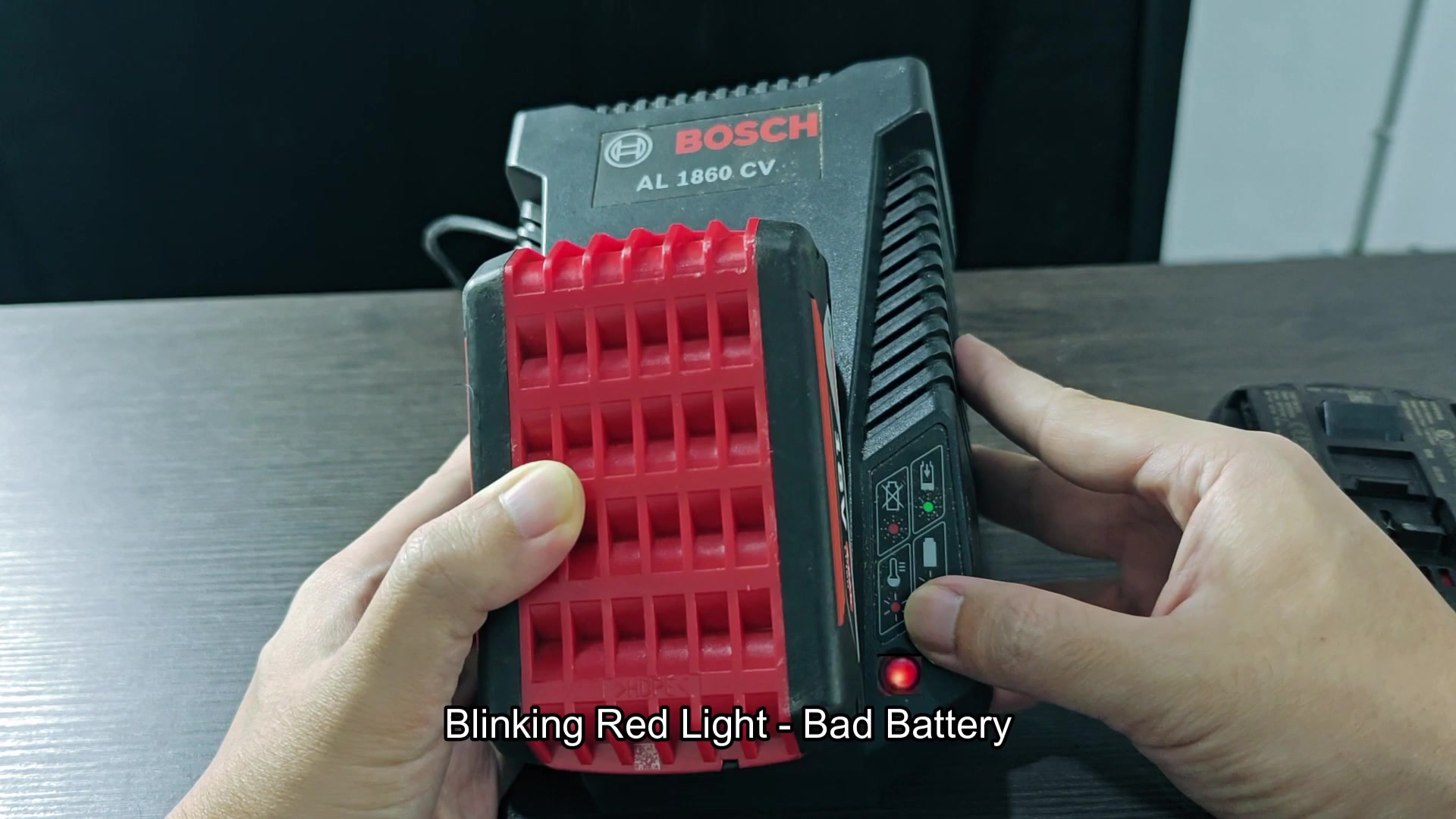 The BOSCH “AL 1860 CV” charger with a red “18V” battery attached is on a table next to another BOSCH battery; the on-screen caption reads “Solid Red Light - Hot Cold Relay,” and a finger is pointing at the solid red indicator light on the charger The BOSCH “AL 1860 CV” charger with a red “18V” battery attached is on a table next to another BOSCH battery; the on-screen caption reads “Solid Red Light - Hot Cold Relay,” and a finger is pointing at the solid red indicator light on the charger